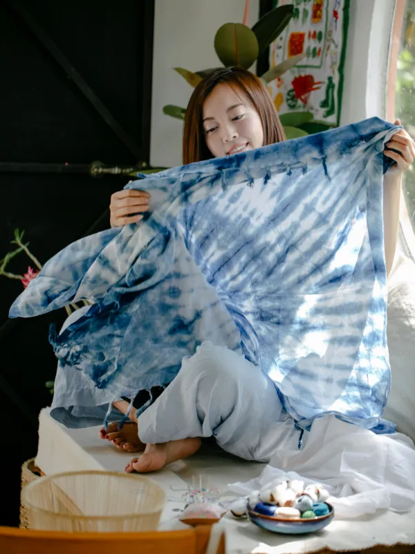 Perajin membentangkan syal katun bermotif shibori biru nila