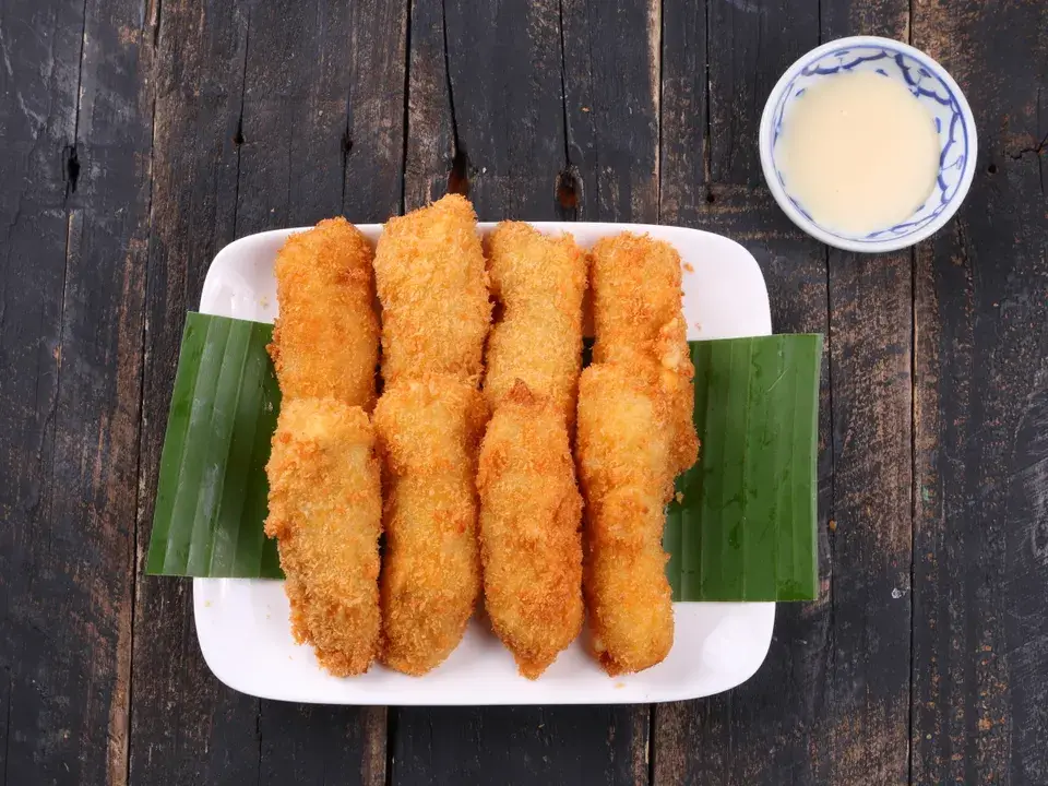 Pisang goreng renyah di atas daun pisang dengan saus cocolan